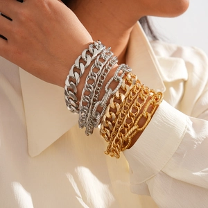 Close-up of a model wearing gold and silver chunky Cuban link bracelets in a layered style