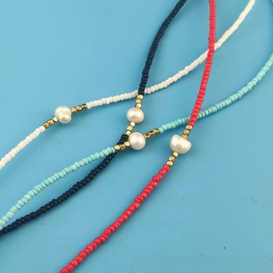 Flat lay of colorful seed bead necklaces with freshwater pearls on a blue background