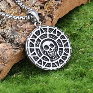 Macro shot of silver skull pendant with Aztec symbols on rustic moss background