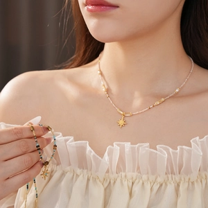 Close-up of gold star pendants on pearl necklaces and bracelets worn by a model