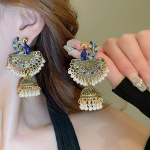 Detailed view of peacock vintage earrings with blue enamel and white pearl tassels