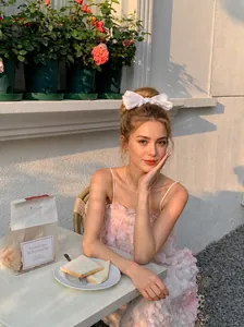 Blue bow hair clip worn by a model in a romantic outdoor setting for a fairy-like style
