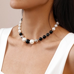 Detail of black and white imitation pearl beaded necklace on model for neck length view