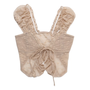 Detail of light apricot lace crop top with ruffled edges and delicate bow tie closure