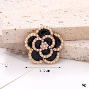 Macro shot of a 2.5cm black camellia flower charm with pearls and golden trim