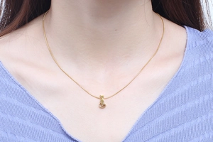 Close-up of a gold cat pendant necklace worn by a model to show the delicate snake chain