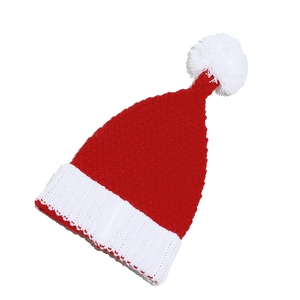 Macro shot of red knit Christmas hat with white pom-pom and thick ribbed texture detail