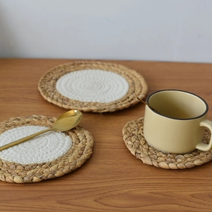 Detailed close-up of woven round coasters in two-tone natural wood and white cotton finish