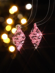 Macro shot of geometric diamond earrings with purple leopard pattern and sparkly beads