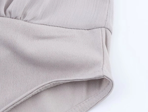 Detail of light gray knit fabric showing fine texture and double-needle stitching quality
