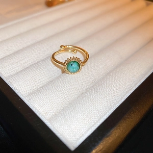 Close-up of 18K gold plated bow ring with turquoise stone inlay in a white jewelry box