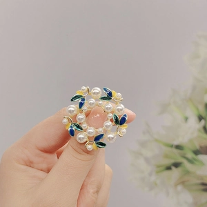 Close-up of vintage wreath brooch with colorful enamel leaves and white pearls