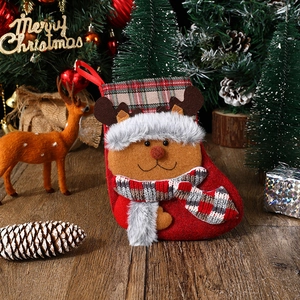 Detail of red Christmas stocking featuring a 3D plush reindeer and plaid scarf decoration