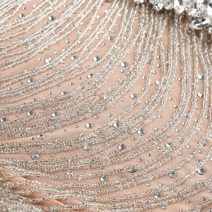 Macro detail of luxury evening gown featuring silver bead fringe and sparkling rhinestones