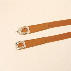 Detail of caramel elastic waist belt featuring a gold rectangular buckle and leather trim