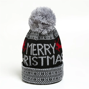 Detailed view of black knitted Christmas hat with Merry Christmas text and red deer