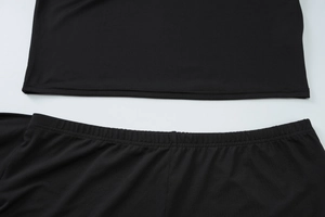 Detailed close-up of elastic waistband and hem stitching on black two-piece summer set