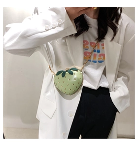 Detail of light green strawberry crossbody bag with golden studs and metal chain strap