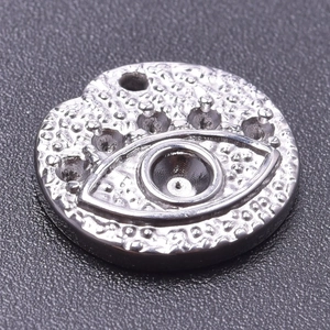 Macro shot of silver evil eye pendant with embossed texture and metal hanging loop