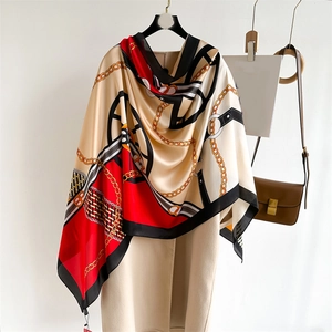 Elegant chain print silk scarf with luxury color blocks draped on a beige winter coat