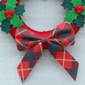 Christmas wreath with red felt base, green holly leaves and red blue plaid bow hanging