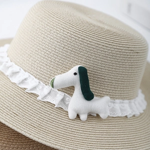 Detailed texture of straw sun hat with white lace trim and knitted puppy ornament