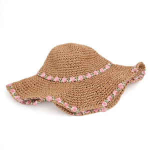 Detail of floral embroidery on wide-brim straw hat with intricate woven texture