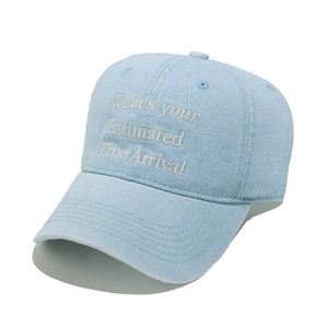 Detailed view of white cursive embroidery on a light blue washed denim baseball cap