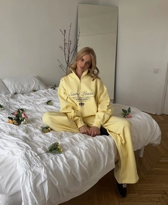 Detail of light yellow tracksuit featuring half-zip sweatshirt and wide-leg sweatpants