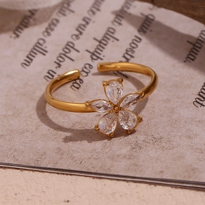Macro shot of gold floral ring with five-petal zircon stones on vintage paper