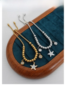 Detailed close-up of beaded starfish pendants on a velvet tray with gold and silver finishes