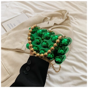Close-up of a green acrylic sphere evening bag with a gold metal frame and handle