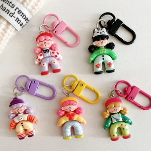 Cute cartoon girl doll keychains in multiple colors on a white textured background