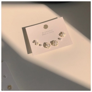 Detail view of elegant white camellia pearl stud earring set with golden finish