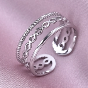 Macro detail of silver three-layer ring with twisted rope and chain texture on pink silk