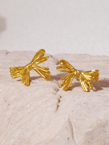 Gros plan de boucles d'oreilles nœud doré sur base en pierre montrant les détails fins