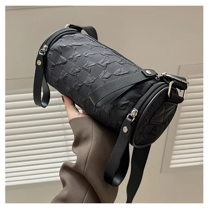 Close-up of black cylinder bag featuring pleated 3D texture and silver metal hardware