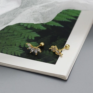 Golden fan-shaped marquise zircon stud earrings displayed on a botanical book page