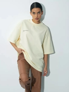 Λεπτομέρεια από κρεμ oversized βαμβακερό μπλουζάκι με τύπωμα γραμμάτων και υφή υφάσματος