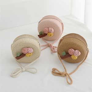 Detail of woven straw shoulder bags featuring decorative fabric flowers and top zippers