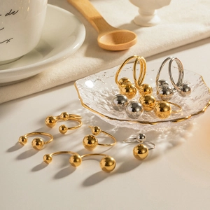 Polished gold and silver ball open rings displayed on an elegant glass tray