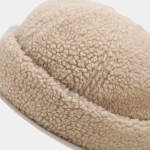 Detailed macro texture of beige lamb wool fabric on a minimalist docker brimless cap