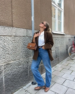 Outdoor street style view of casual brown suede blazer paired with dark straight-leg jeans