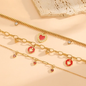 Détail de trois chaînes en acier plaqué or 18 carats avec cœurs rouges et cristaux