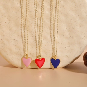 Close-up of heart enamel pendants in pink, red, and blue on 14K gold plated chains