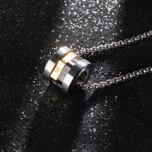 Macro shot of tricolor titanium steel cylindrical pendant with roman numeral engraving