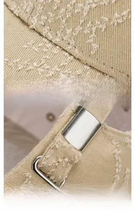 Detail of adjustable metal buckle and distressed cotton fabric texture on beige baseball cap