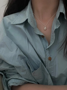Close-up of minimalist S925 silver necklace with a natural freshwater pearl on a blue shirt
