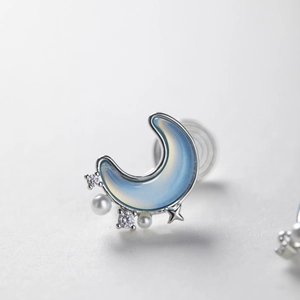Macro shot of silver moon earring with light blue opal texture and small white pearls