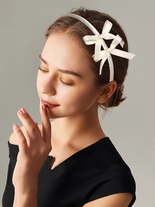 Close-up of white satin double bow headband worn by a model in ballet style